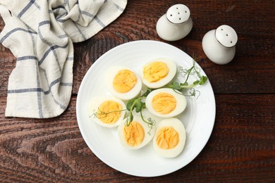 Photo of Boiled eggs and microgreens on wooden table, flat lay