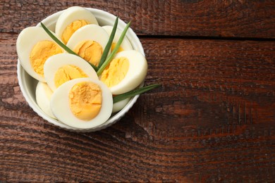Photo of Boiled eggs and green onions on wooden table, top view. Space for text