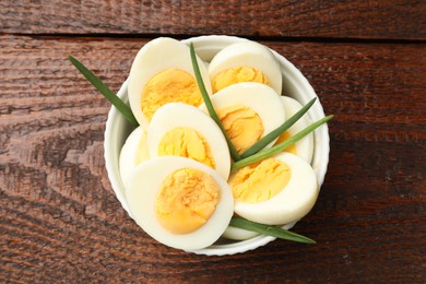 Photo of Boiled eggs and green onions on wooden table, top view