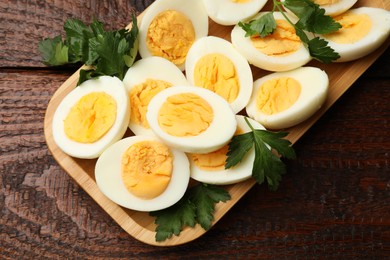 Photo of Boiled eggs and parsley on wooden table, top view
