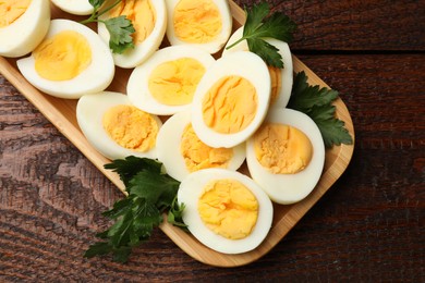 Photo of Boiled eggs and parsley on wooden table, top view