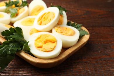 Photo of Boiled eggs and parsley on wooden table, closeup