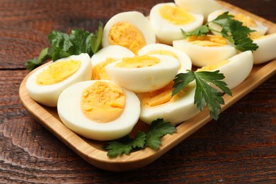 Photo of Boiled eggs and parsley on wooden table, closeup