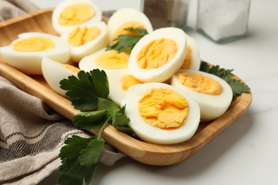 Photo of Boiled eggs and parsley on white marble table, closeup