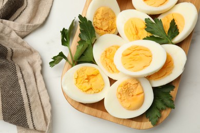 Photo of Boiled eggs and parsley on white marble table, top view