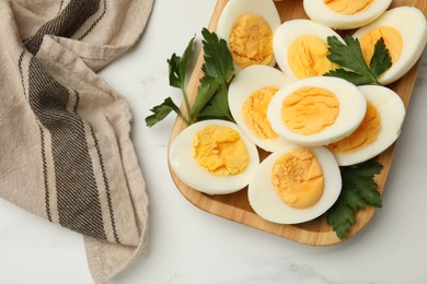 Photo of Boiled eggs and parsley on white marble table, top view