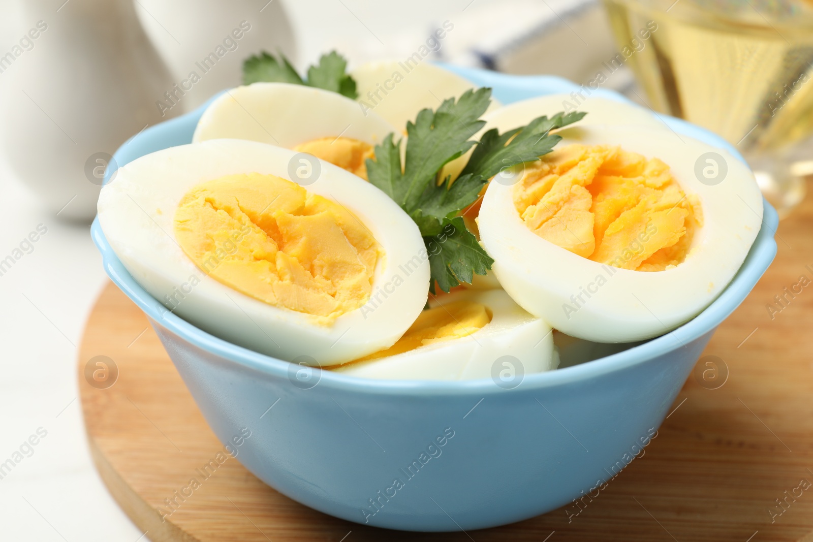Photo of Boiled eggs and parsley in bowl on table, closeup