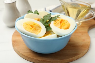 Photo of Boiled eggs, parsley and oil on white table, closeup