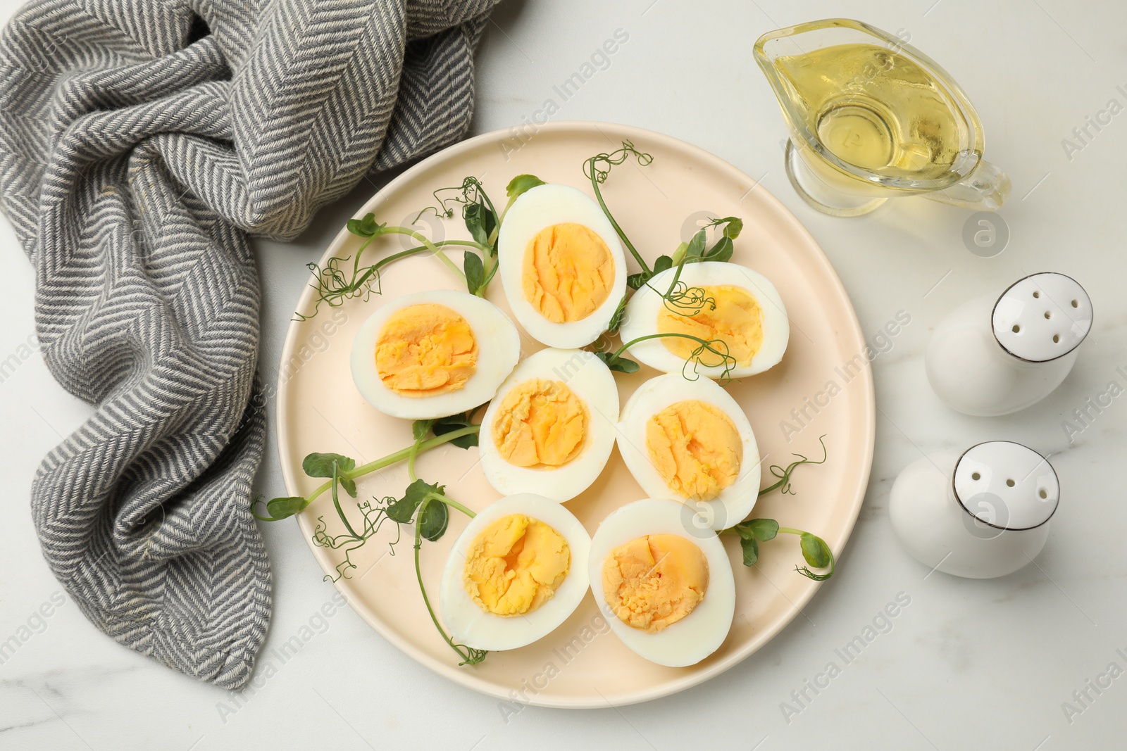 Boiled eggs, microgreens and oil on white marble table, flat lay Photo of Boiled eggs, microgreens and oil on white marble table, flat lay