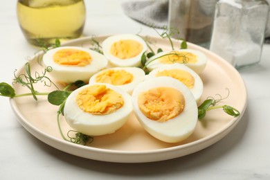 Photo of Boiled eggs and microgreens on white marble table, closeup