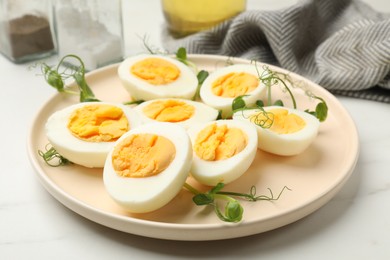 Photo of Boiled eggs and microgreens on white marble table, closeup