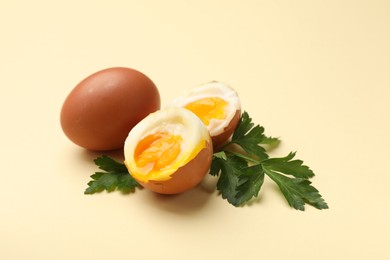 Photo of Soft boiled eggs and parsley on beige background, closeup