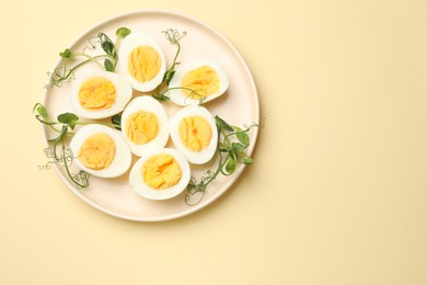 Photo of Boiled eggs and microgreens on beige background, top view. Space for text