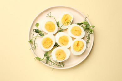 Photo of Boiled eggs and microgreens on beige background, top view