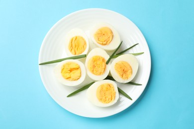 Photo of Boiled eggs and green onions on light blue background, top view