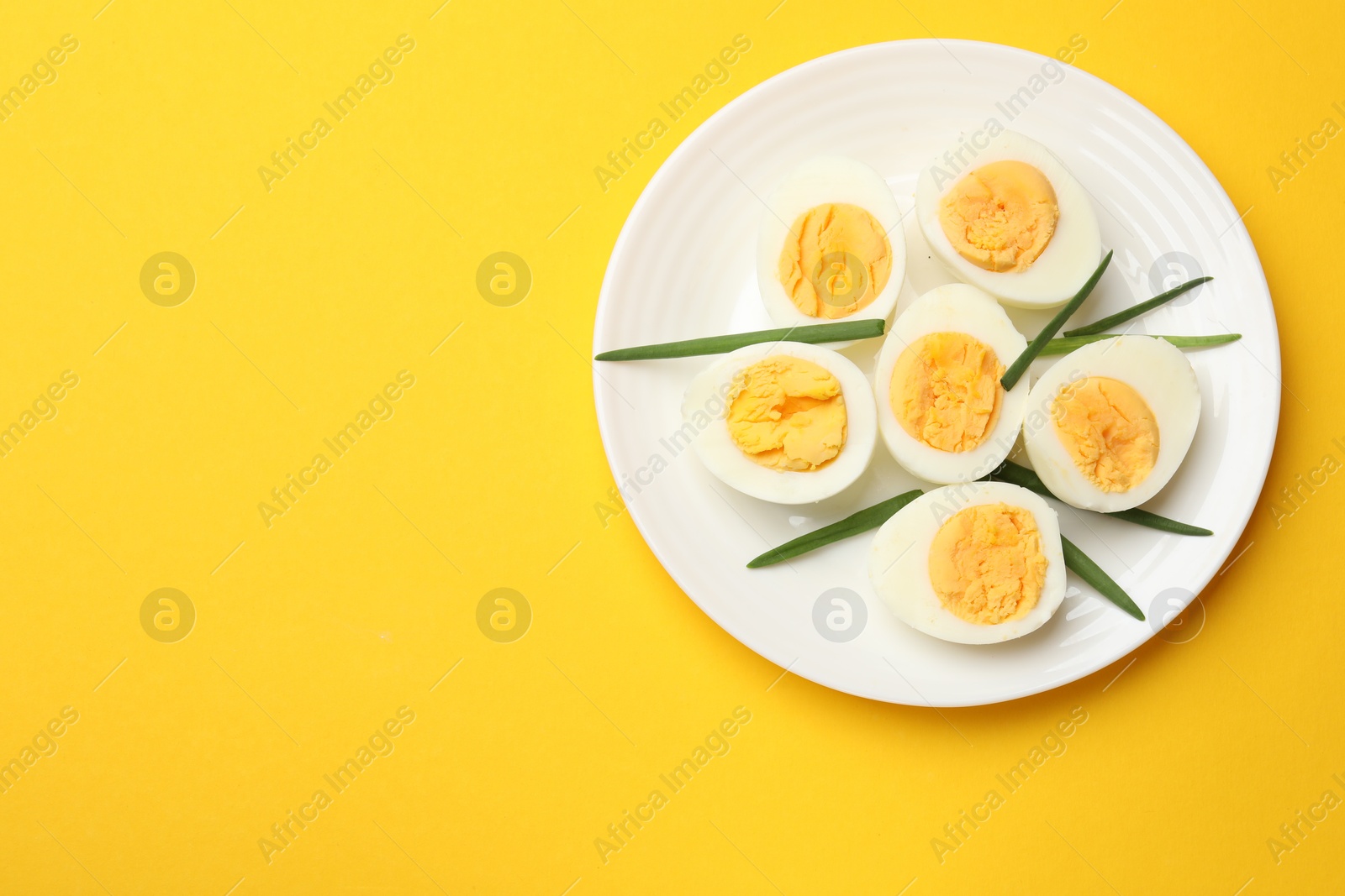 Boiled eggs and green onions on yellow background, top view. Space for text Photo of Boiled eggs and green onions on yellow background, top view. Space for text