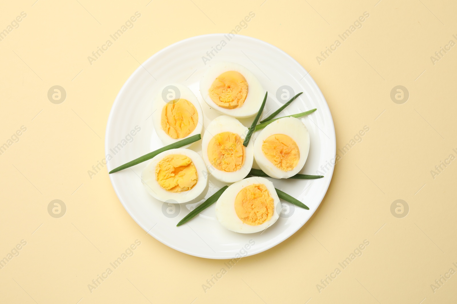 Photo of Boiled eggs and green onions on beige background, top view