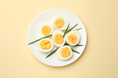 Photo of Boiled eggs and green onions on beige background, top view