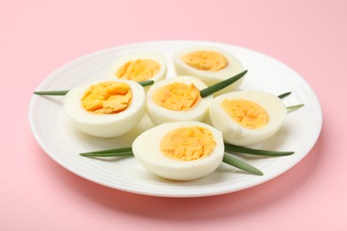 Photo of Boiled eggs and green onions on pink background, closeup