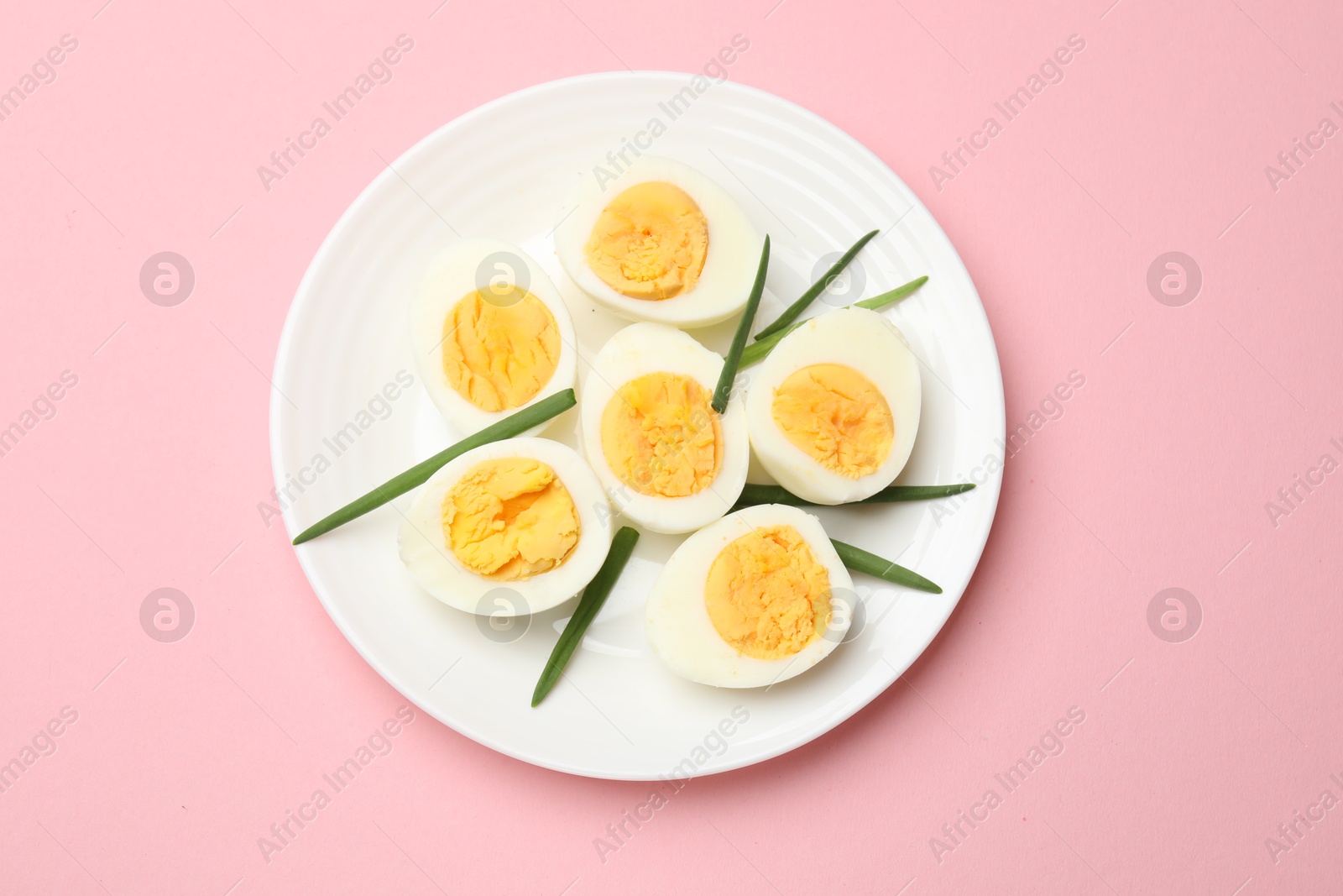 Boiled eggs and green onions on pink background, top view Photo of Boiled eggs and green onions on pink background, top view