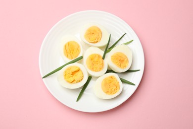 Photo of Boiled eggs and green onions on pink background, top view