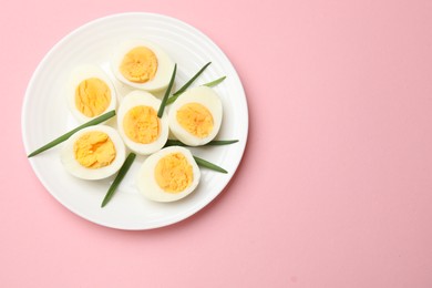 Photo of Boiled eggs and green onions on pink background, top view. Space for text