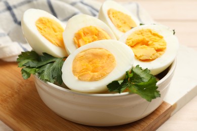 Photo of Boiled eggs and parsley in bowl on table, closeup