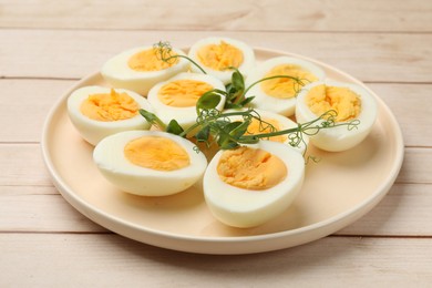 Photo of Boiled eggs and microgreens on wooden table, closeup