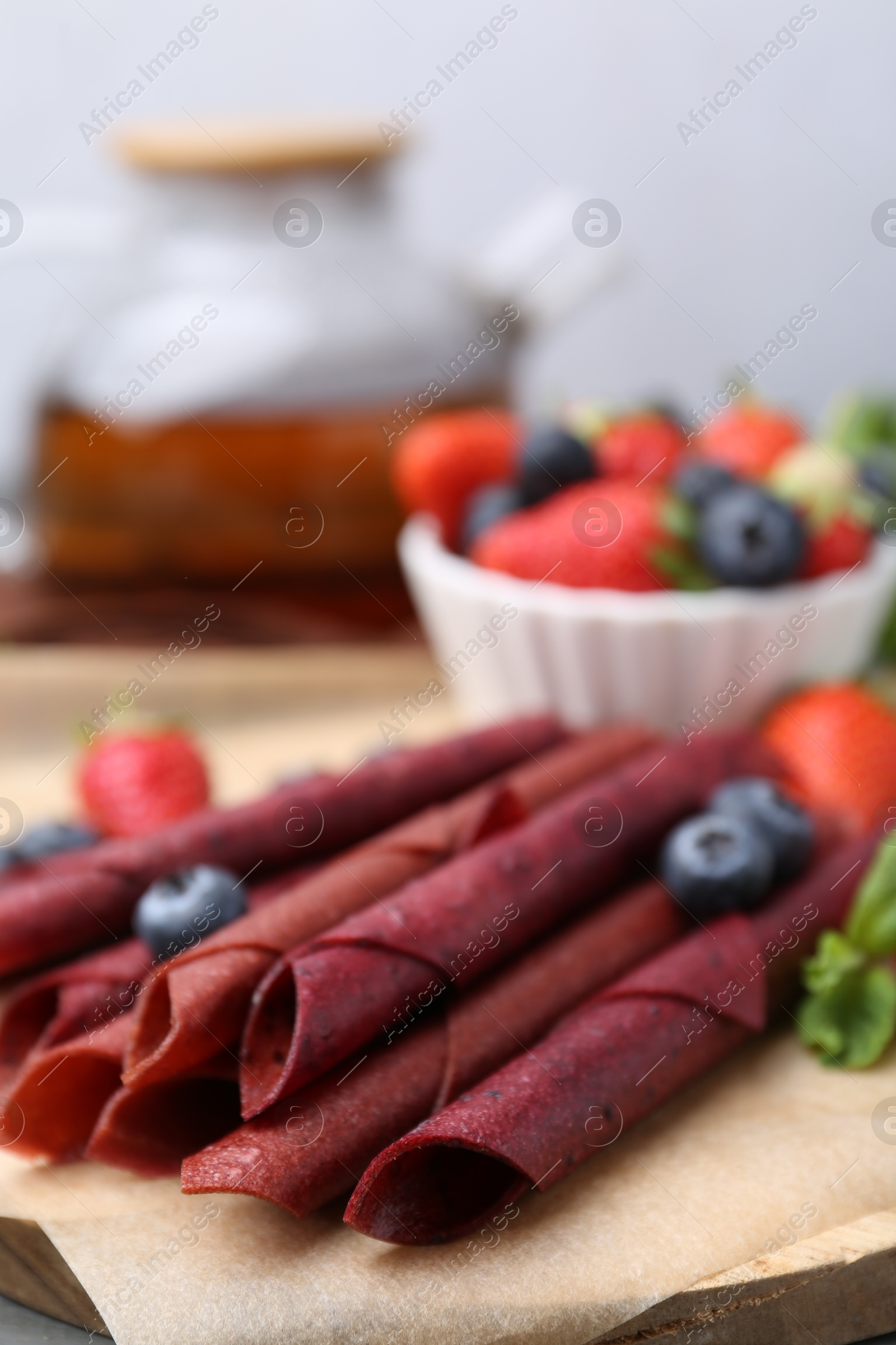 Tasty fruit leather rolls, strawberries, blueberries and mint on table, closeup Photo of Tasty fruit leather rolls, strawberries, blueberries and mint on table, closeup