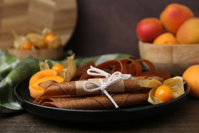 Photo of Tasty fruit leather, physalis and apricots on wooden table, closeup