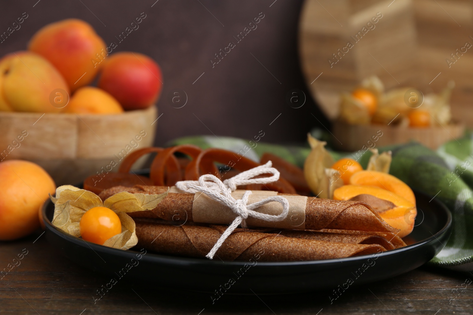 Tasty fruit leather, physalis and apricots on wooden table, closeup Photo of Tasty fruit leather, physalis and apricots on wooden table, closeup