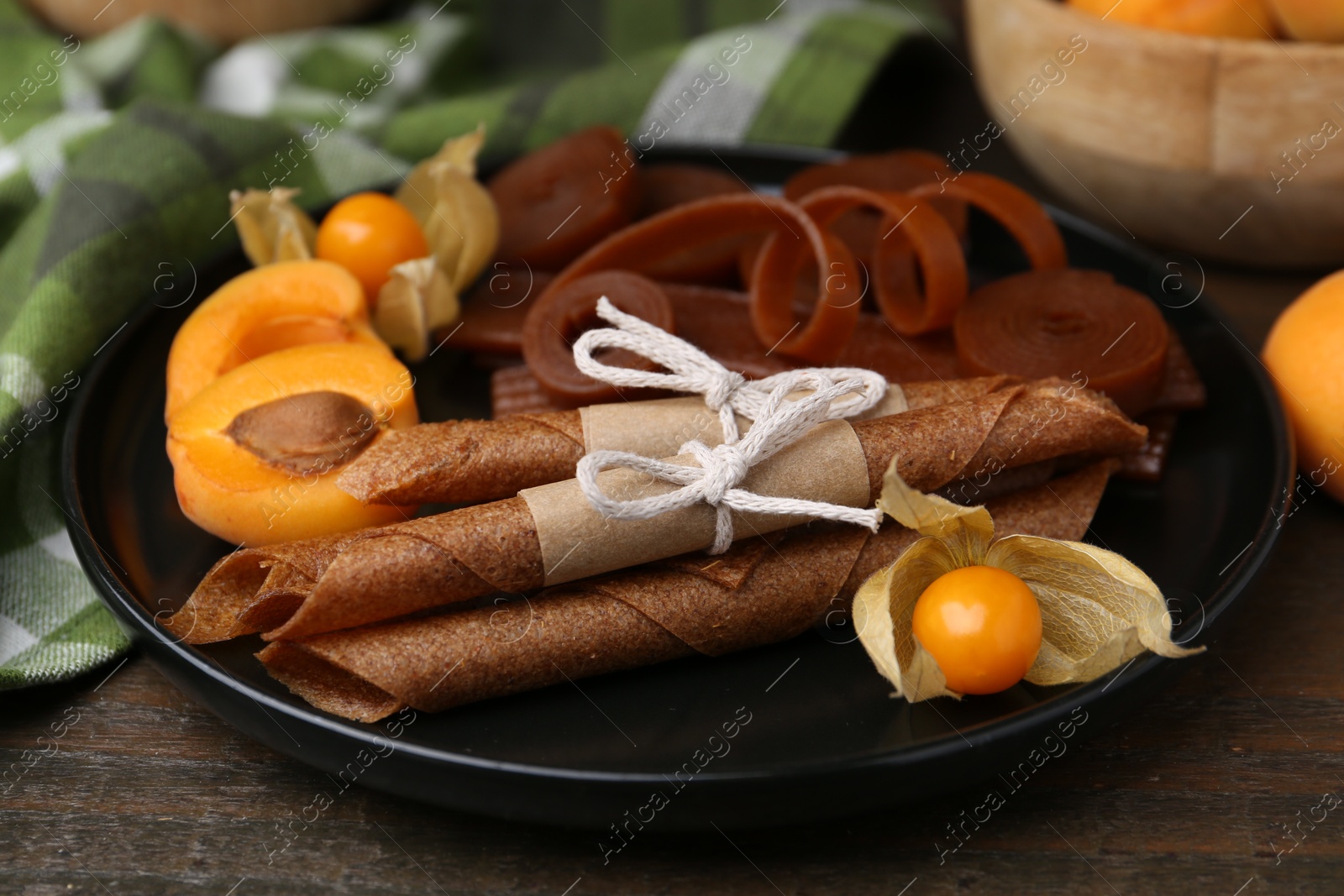 Tasty fruit leather, physalis and apricots on wooden table, closeup Photo of Tasty fruit leather, physalis and apricots on wooden table, closeup