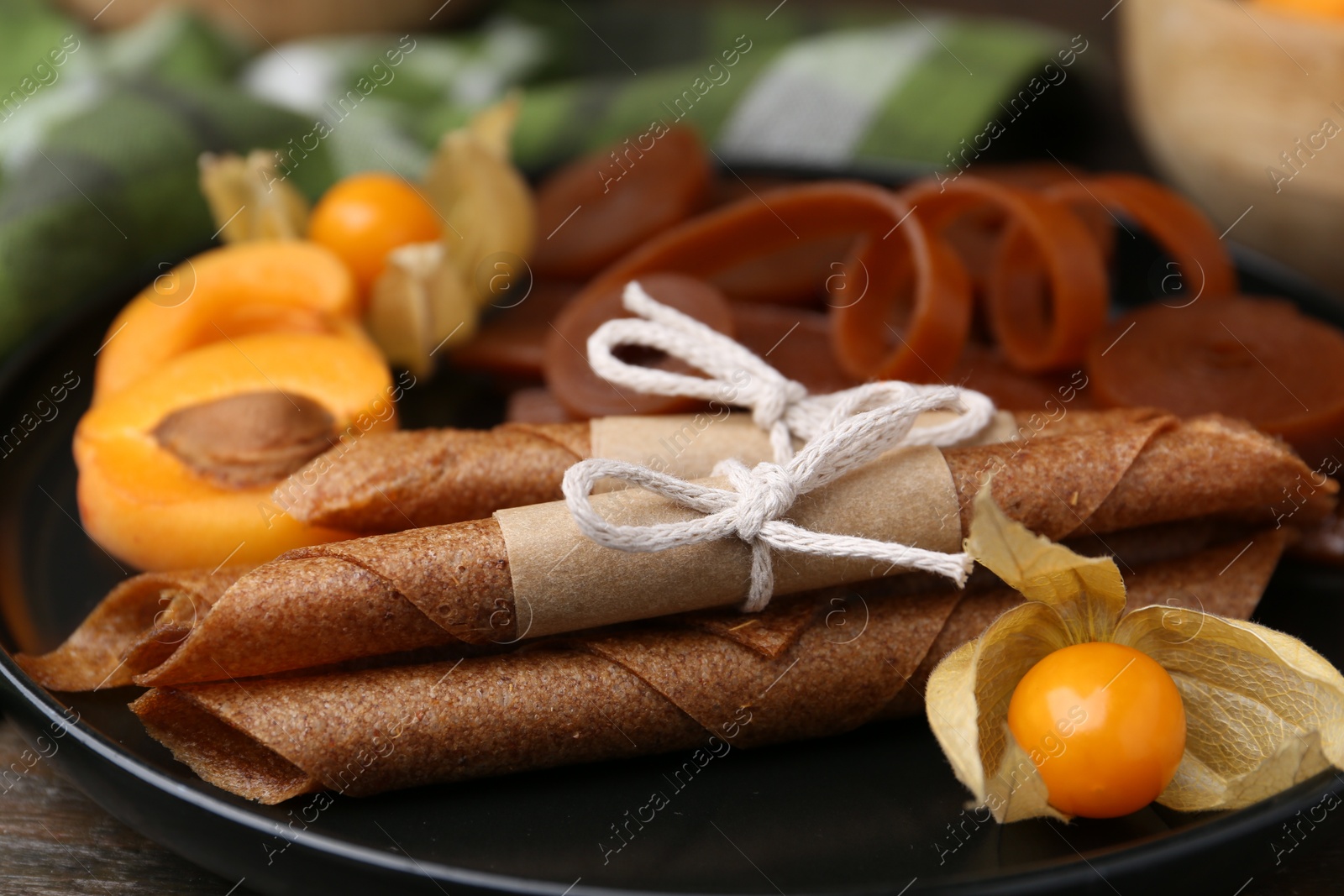 Tasty fruit leather, physalis and apricots on wooden table, closeup Photo of Tasty fruit leather, physalis and apricots on wooden table, closeup