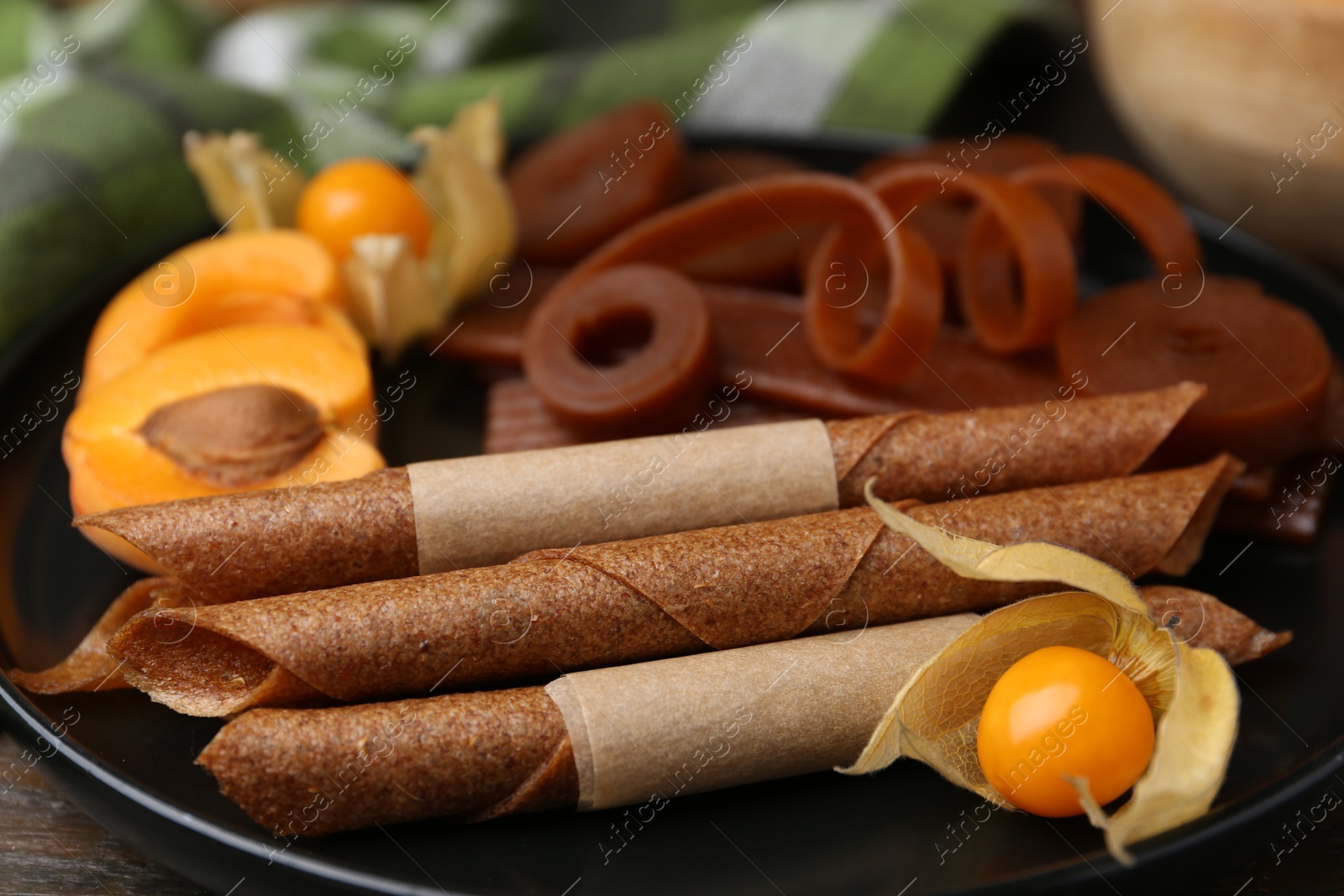 Tasty fruit leather, physalis and apricots on wooden table, closeup Photo of Tasty fruit leather, physalis and apricots on wooden table, closeup