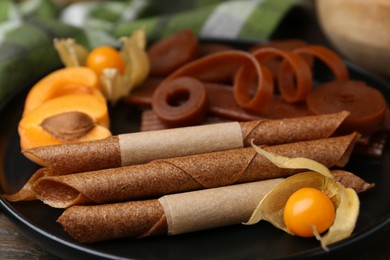 Photo of Tasty fruit leather, physalis and apricots on wooden table, closeup