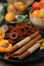 Photo of Tasty fruit leather, physalis and apricots on wooden table, closeup