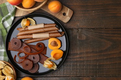 Photo of Tasty fruit leather, physalis and apricots on wooden table, flat lay. Space for text
