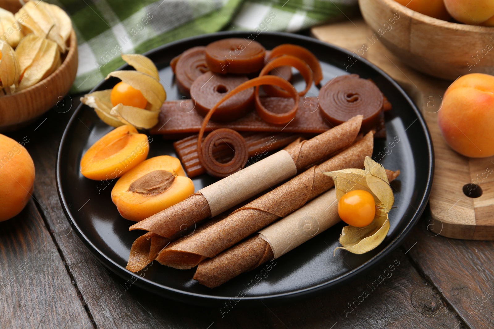 Tasty fruit leather, physalis and apricots on wooden table, closeup Photo of Tasty fruit leather, physalis and apricots on wooden table, closeup