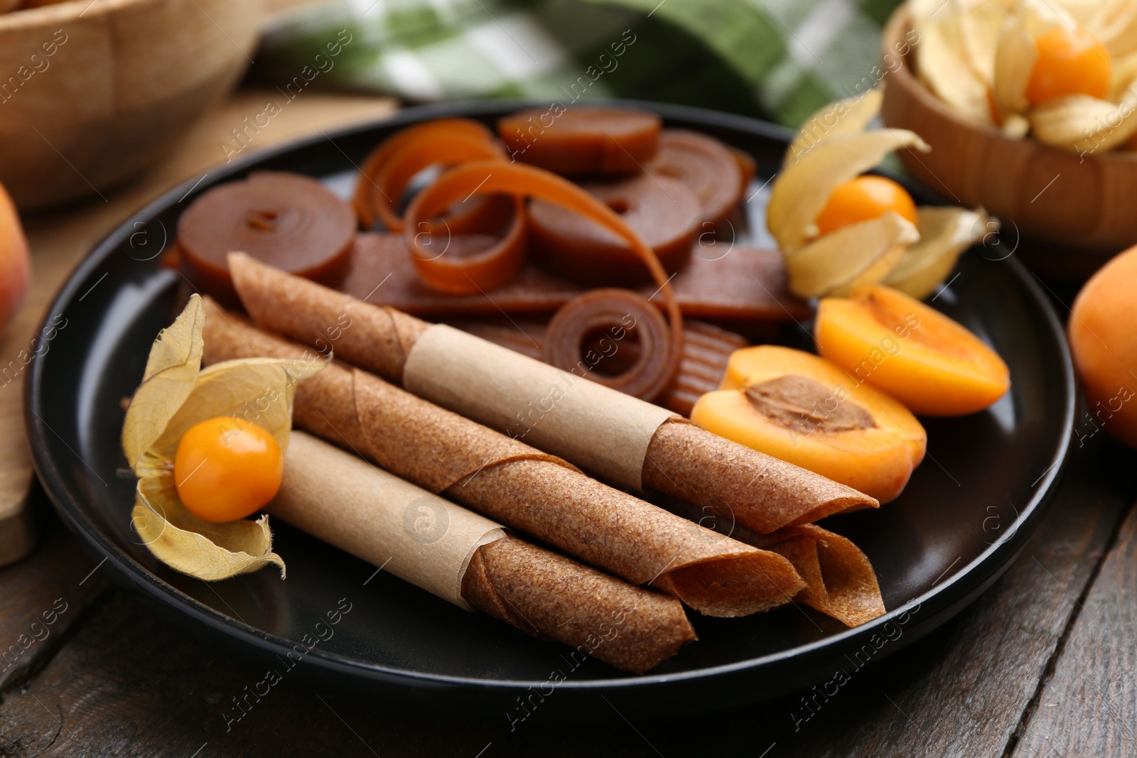 Tasty fruit leather, physalis and apricots on wooden table, closeup Photo of Tasty fruit leather, physalis and apricots on wooden table, closeup