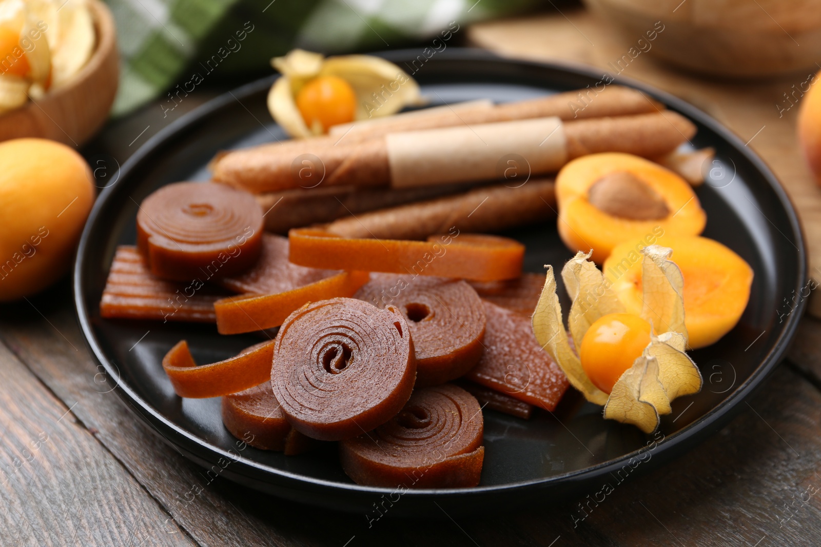 Tasty fruit leather, physalis and apricots on wooden table, closeup Photo of Tasty fruit leather, physalis and apricots on wooden table, closeup