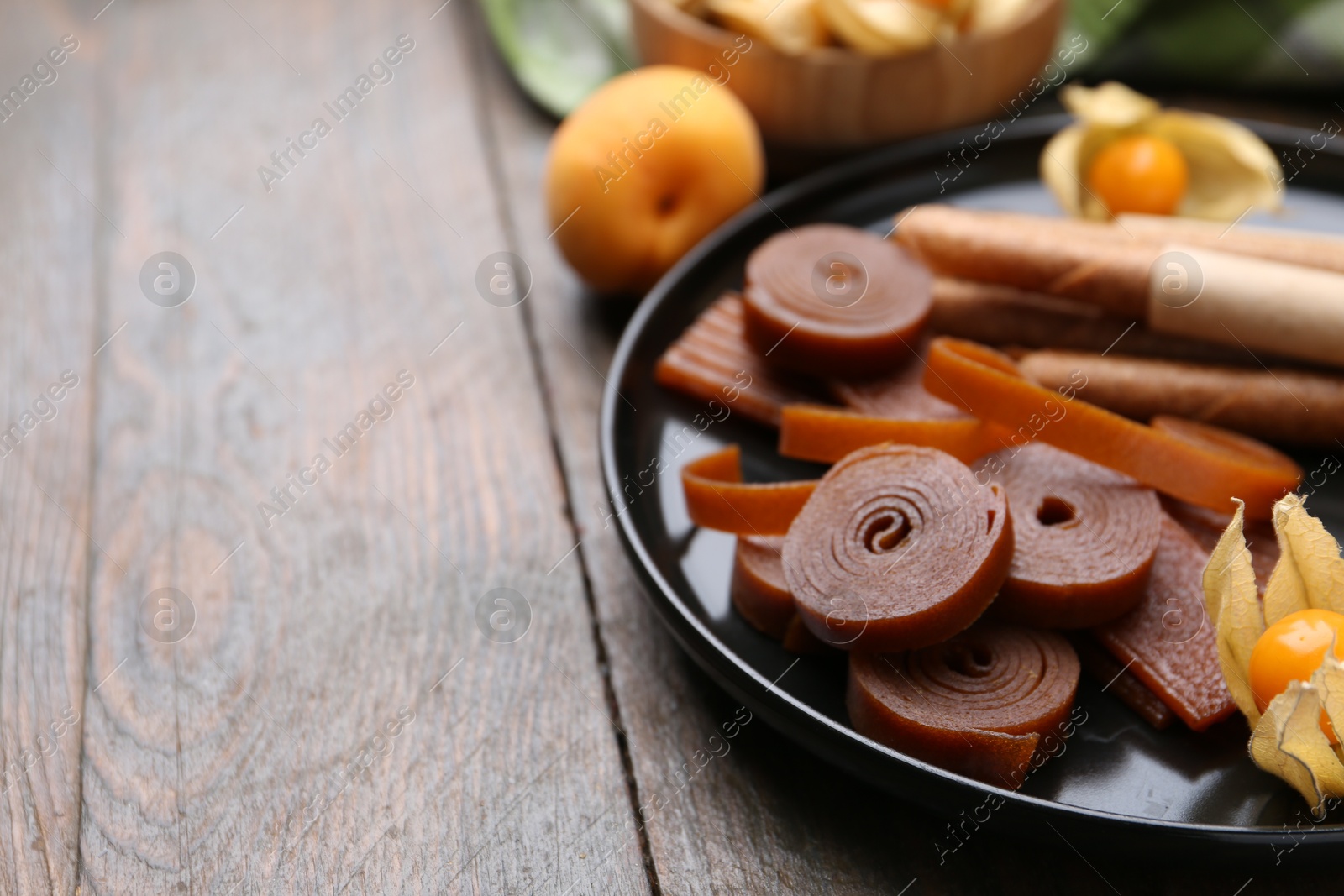Tasty fruit leather, physalis and apricots on wooden table, closeup. Space for text Photo of Tasty fruit leather, physalis and apricots on wooden table, closeup. Space for text