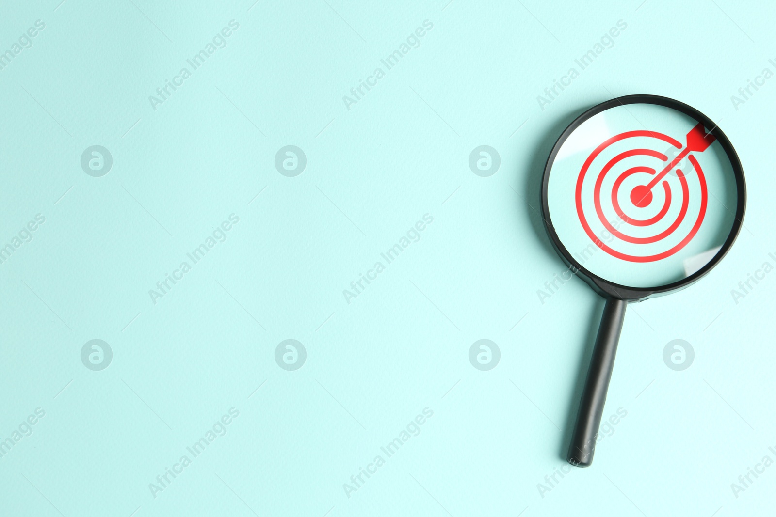 Targeting. Magnifying glass with bullseye inside on light turquoise background, top view. Space for text Image of Targeting. Magnifying glass with bullseye inside on light turquoise background, top view. Space for text