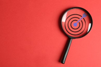Image of Targeting. Magnifying glass with bullseye inside on red background, top view. Space for text