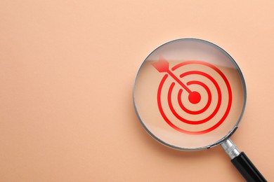 Image of Targeting. Magnifying glass with bullseye inside on dark beige background, top view. Space for text
