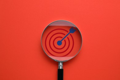 Image of Targeting. Magnifying glass with bullseye inside on red background, top view