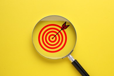 Image of Targeting. Magnifying glass with bullseye inside on yellow background, top view