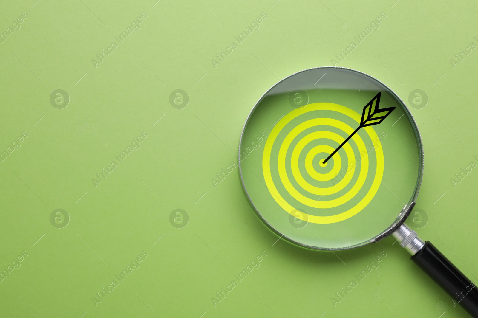 Targeting. Magnifying glass with bullseye inside on light green background, top view. Space for text Image of Targeting. Magnifying glass with bullseye inside on light green background, top view. Space for text