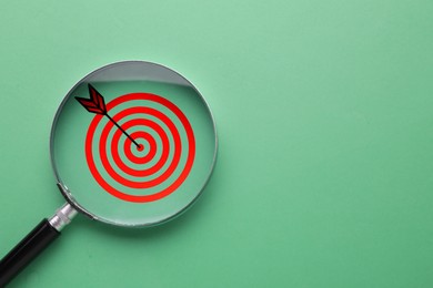 Image of Targeting. Magnifying glass with bullseye inside on turquoise background, top view. Space for text
