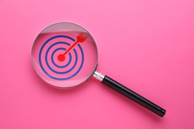 Image of Targeting. Magnifying glass with bullseye inside on pink background, top view. Space for text