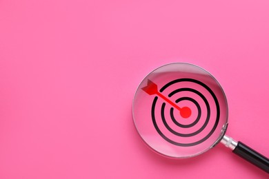 Image of Targeting. Magnifying glass with bullseye inside on pink background, top view. Space for text